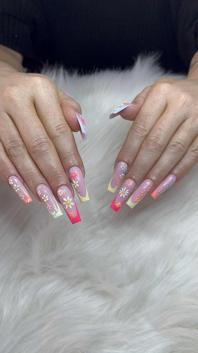 Hände mit bunten, langen Kunstnägeln auf einem flauschigen Untergrund.